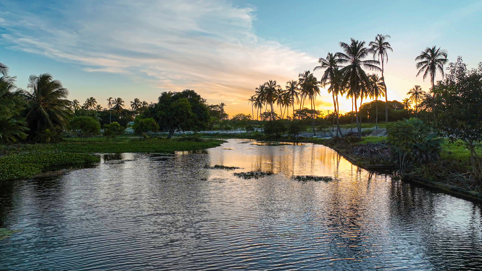 Lagoa e coqueiros ao pôr do sol no Villa Prabhu, em Paracuru
